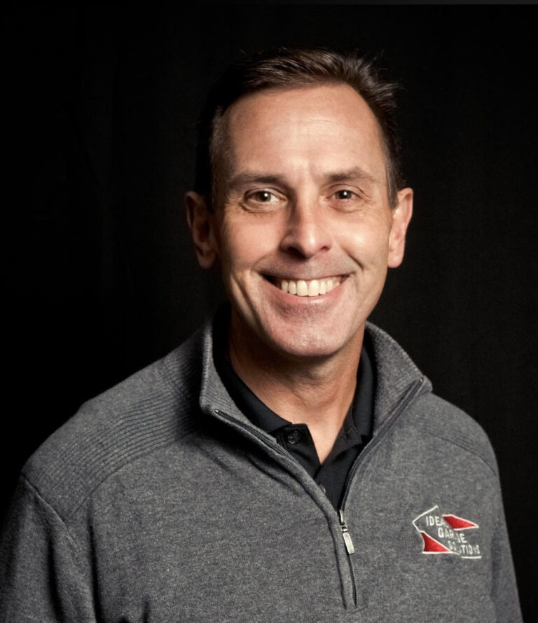 Smiling man in gray zip-up jacket with "De Garde Brewing" logo on chest.